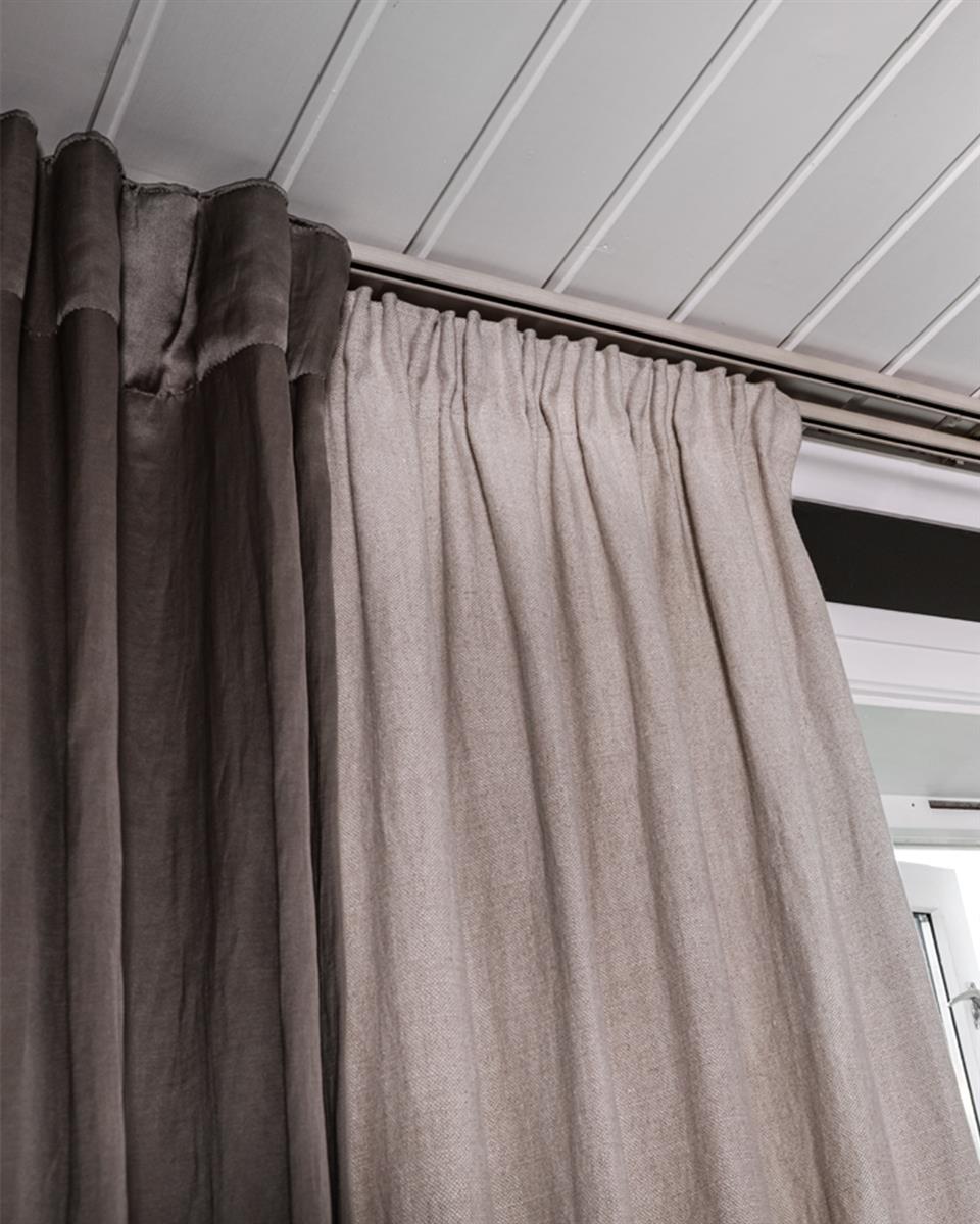 Detaljbilde av dobbel gardinskinne og to lag med gardiner. Foto.